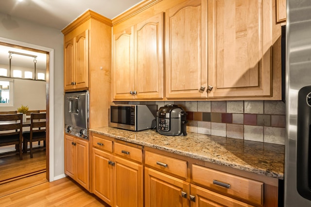 kitchen with light stone countertops, tasteful backsplash, stainless steel appliances, and light wood-style flooring