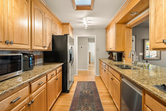 kitchen featuring light brown cabinetry, sink, light stone counters, light wood-type flooring, and stainless steel appliances