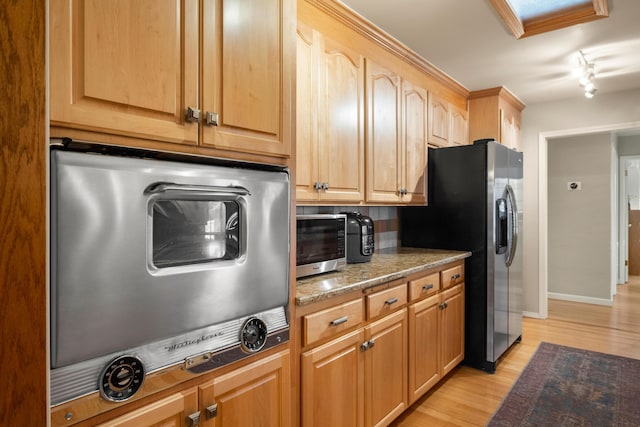 kitchen with stainless steel fridge, backsplash, light stone counters, light wood-type flooring, and light brown cabinets