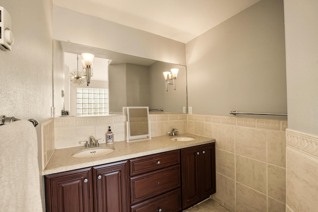 full bath featuring tile walls, a chandelier, a sink, and wainscoting