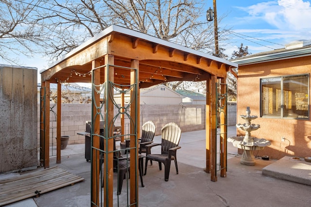 view of patio featuring fence, an outbuilding, and a gazebo