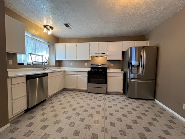 kitchen featuring light countertops, appliances with stainless steel finishes, white cabinetry, under cabinet range hood, and baseboards