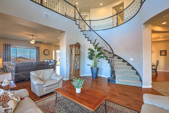 living room with ceiling fan, hardwood / wood-style floors, and a high ceiling