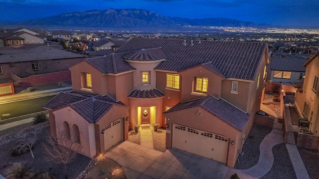 view of front of home featuring a tiled roof, a mountain view, concrete driveway, and stucco siding