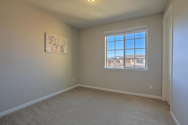 carpeted empty room featuring a textured ceiling