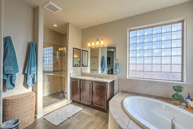 bathroom featuring vanity, plus walk in shower, and a textured ceiling