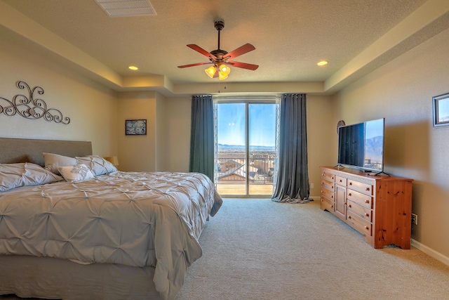 bedroom featuring access to outside, light colored carpet, a textured ceiling, and a tray ceiling