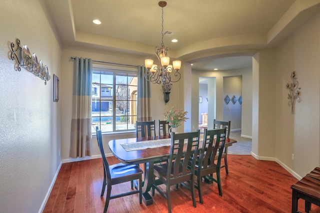 dining area featuring hardwood / wood-style floors, a tray ceiling, and a chandelier