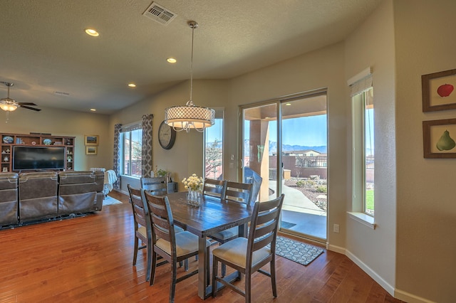 dining room with wood-type flooring, a mountain view, ceiling fan, and a textured ceiling