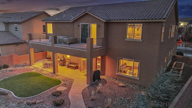 back house at dusk with a patio area and a balcony