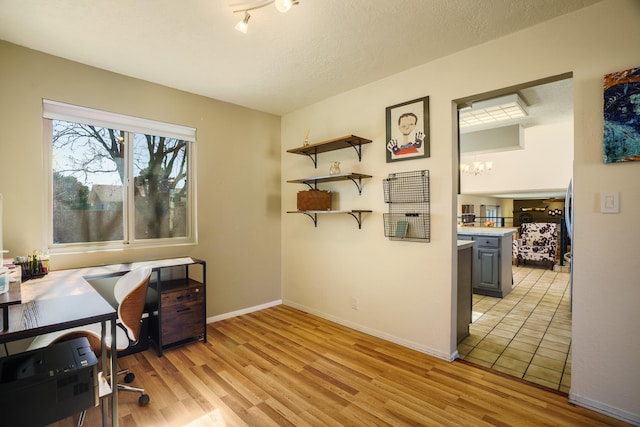 home office featuring a notable chandelier, a textured ceiling, and light hardwood / wood-style flooring