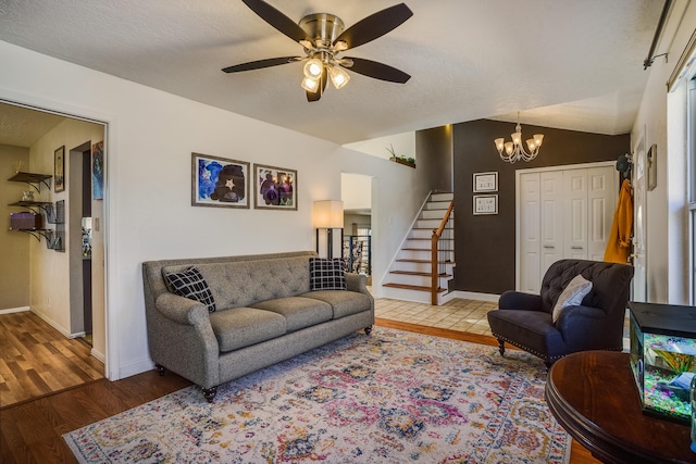 living room with ceiling fan with notable chandelier, vaulted ceiling, hardwood / wood-style floors, and a textured ceiling