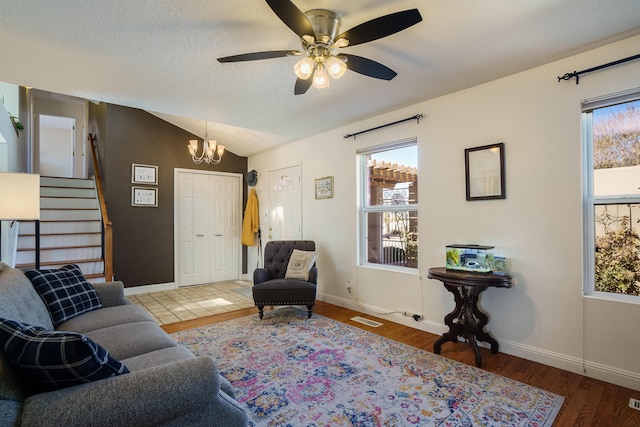 living room featuring a textured ceiling, vaulted ceiling, wood-type flooring, and ceiling fan with notable chandelier