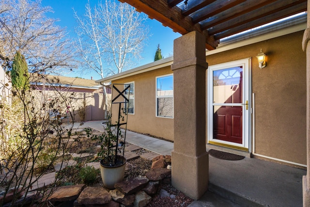 view of exterior entry with a pergola and a patio area