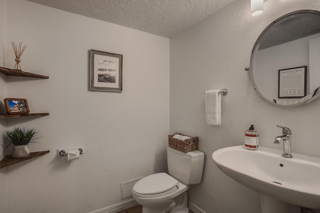 bathroom with sink, toilet, and a textured ceiling