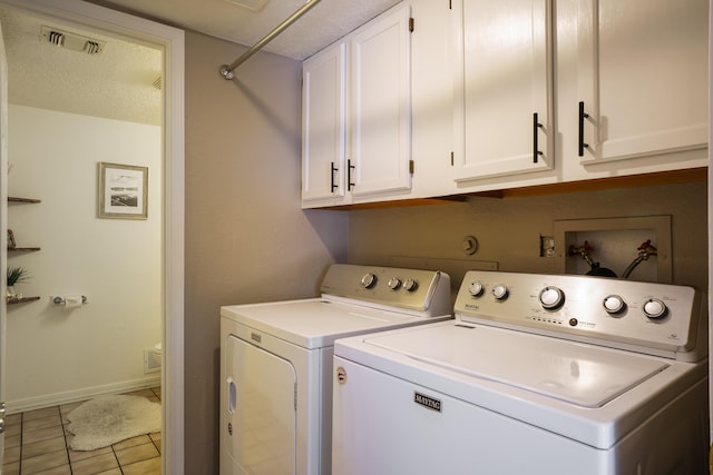 clothes washing area featuring cabinets, washing machine and dryer, light tile patterned flooring, and a textured ceiling