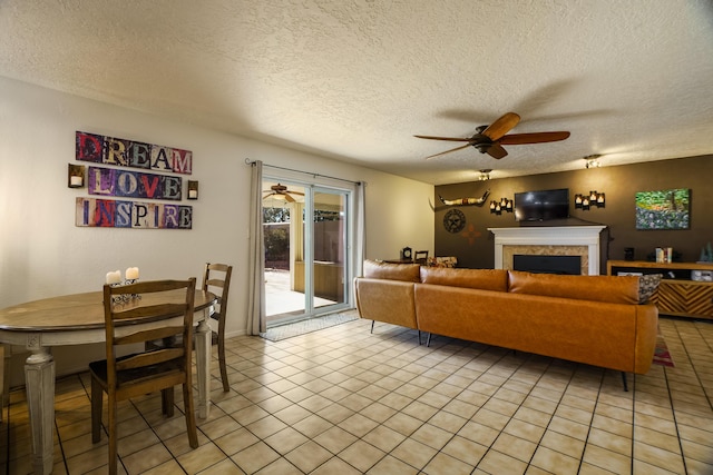 living room with light tile patterned flooring, a textured ceiling, and ceiling fan