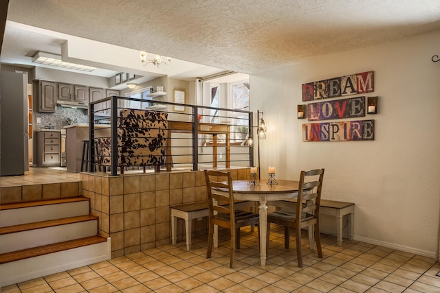 tiled dining space featuring a textured ceiling and a notable chandelier