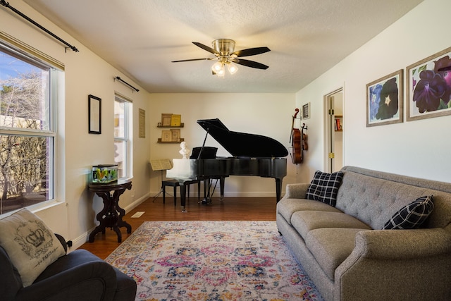 sitting room featuring dark wood-type flooring, ceiling fan, and a textured ceiling