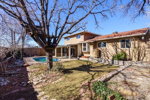 back of property with a fenced in pool, a patio, and a lawn