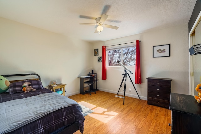 bedroom featuring ceiling fan, light hardwood / wood-style floors, and a textured ceiling