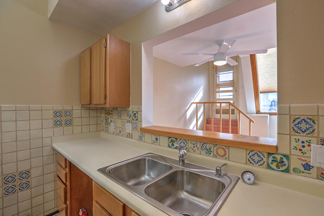 kitchen featuring ceiling fan, sink, and tile walls