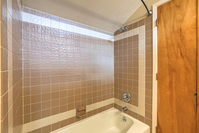 bathroom featuring tiled shower / bath combo, vaulted ceiling, and a textured ceiling