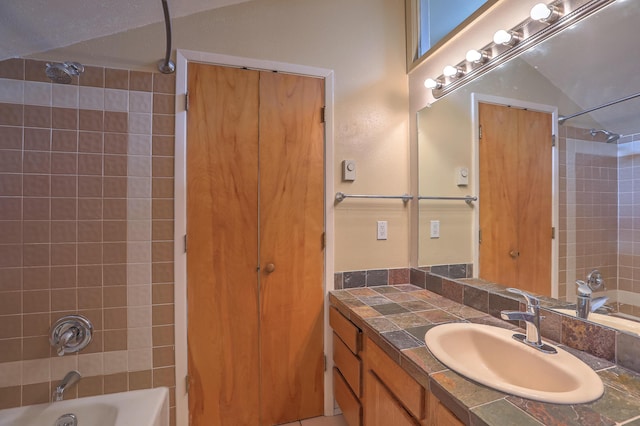 bathroom with tiled shower / bath and vanity