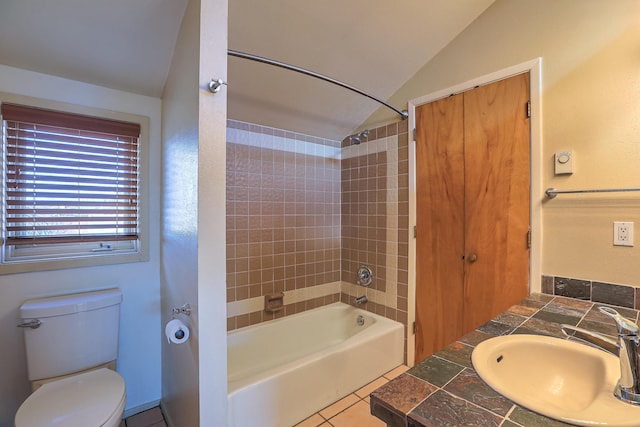 full bathroom featuring vaulted ceiling, tiled shower / bath combo, tile patterned flooring, vanity, and toilet