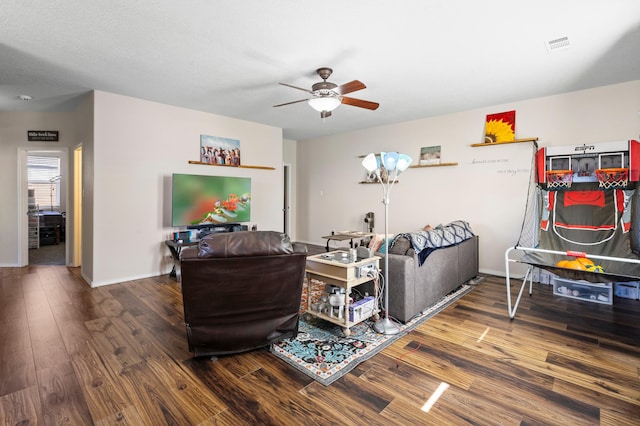 living area featuring a ceiling fan, visible vents, baseboards, and wood finished floors