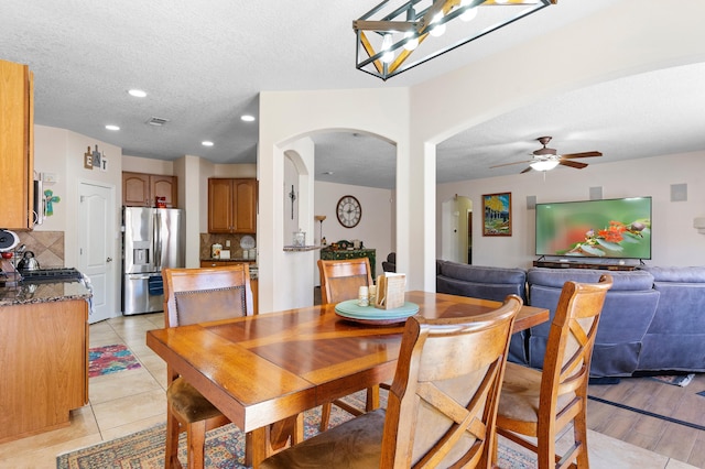 dining room featuring arched walkways, light tile patterned floors, a textured ceiling, recessed lighting, and a ceiling fan