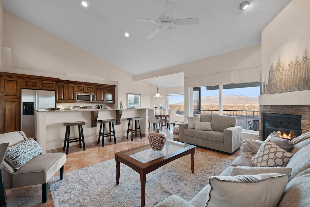 tiled living room with a mountain view, a fireplace, high vaulted ceiling, and ceiling fan