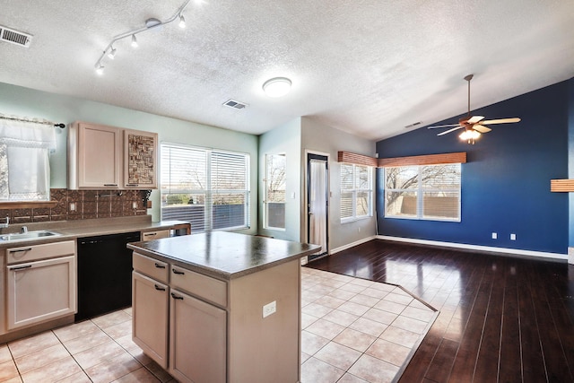 kitchen with a center island, vaulted ceiling, light wood-type flooring, black dishwasher, and backsplash