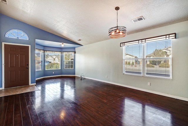 foyer entrance with wood-type flooring, vaulted ceiling, and a textured ceiling