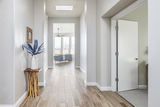 hallway with light hardwood / wood-style flooring and a skylight