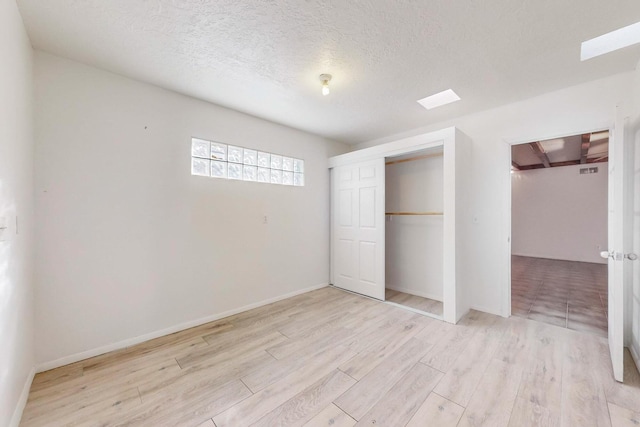 unfurnished bedroom featuring a closet, a textured ceiling, and light hardwood / wood-style flooring