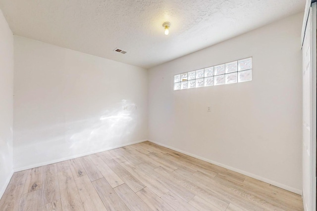 spare room featuring a textured ceiling and light wood-type flooring