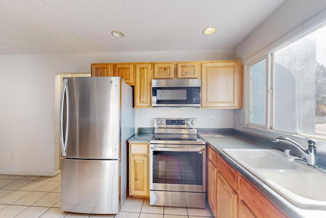 kitchen featuring light tile patterned flooring, stainless steel appliances, sink, and a textured ceiling