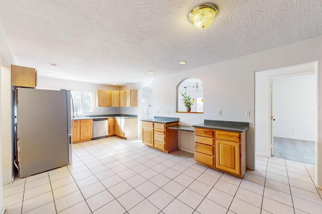 kitchen featuring stainless steel appliances, a textured ceiling, and light tile patterned floors