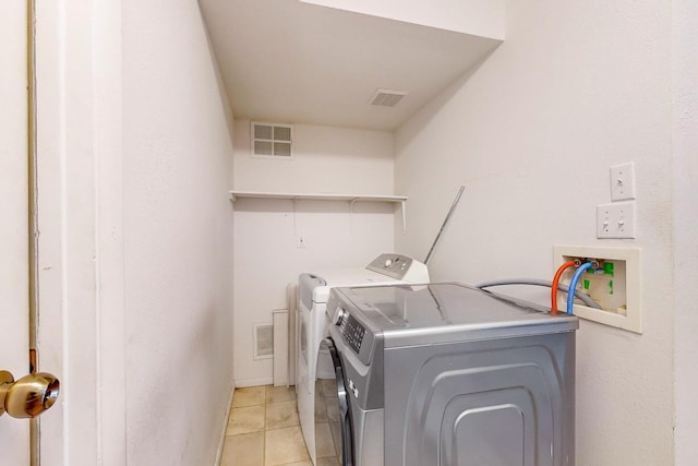 clothes washing area featuring washer and clothes dryer and light tile patterned floors