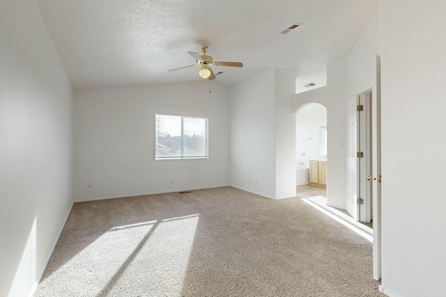 empty room featuring ceiling fan, lofted ceiling, light carpet, and a textured ceiling