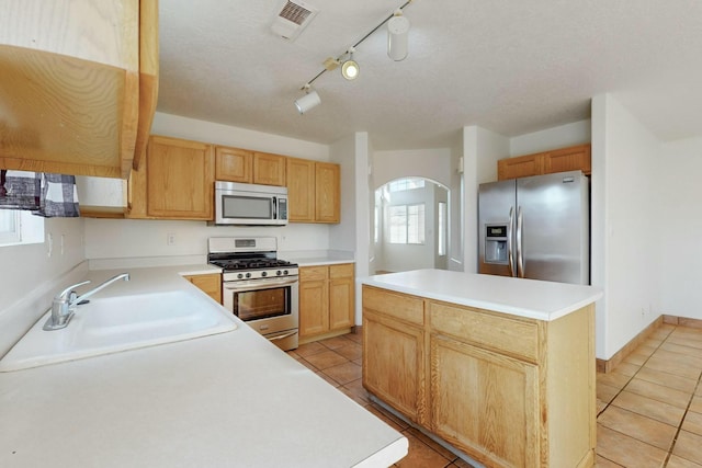 kitchen with stainless steel appliances, a kitchen island, sink, and a wealth of natural light