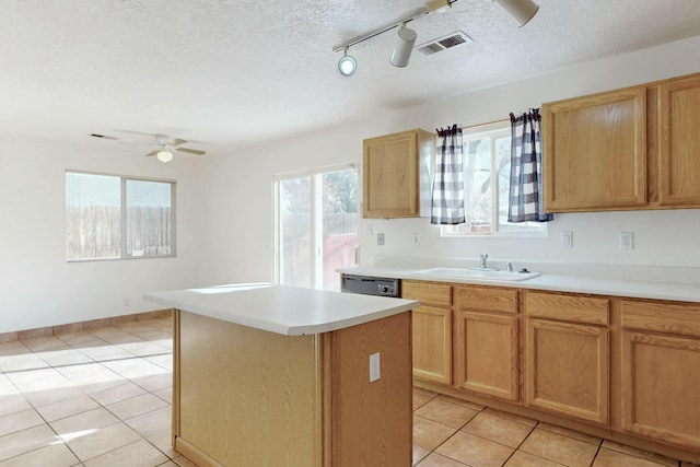 kitchen with sink, dishwasher, ceiling fan, a textured ceiling, and a kitchen island