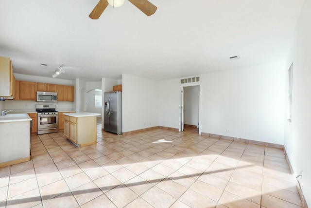 kitchen with stainless steel appliances, a center island, sink, and light tile patterned floors