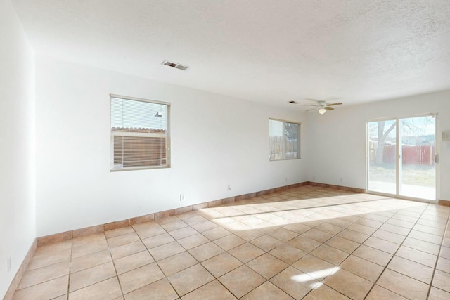 tiled empty room with ceiling fan and a textured ceiling