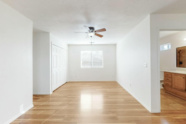 unfurnished room with ceiling fan, plenty of natural light, a textured ceiling, and light hardwood / wood-style floors