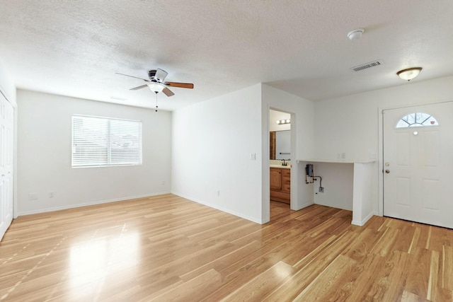 foyer entrance with ceiling fan, light hardwood / wood-style flooring, sink, and a textured ceiling