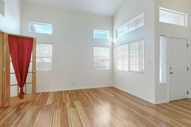 foyer entrance with a towering ceiling and light wood-type flooring