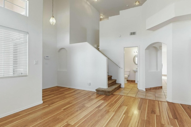 unfurnished living room with a towering ceiling and light hardwood / wood-style floors