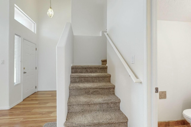 stairs with hardwood / wood-style floors and a towering ceiling